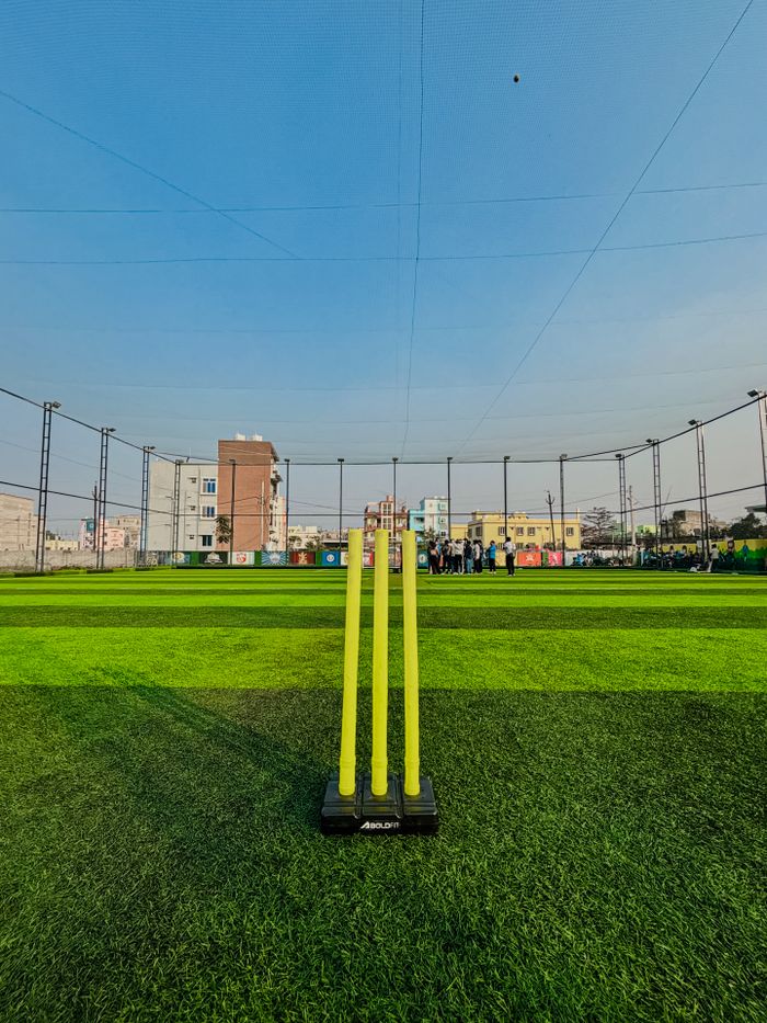 gallery-4 Vibrant cricket pitch scene with stumps and buildings in Bhubaneswar, India.