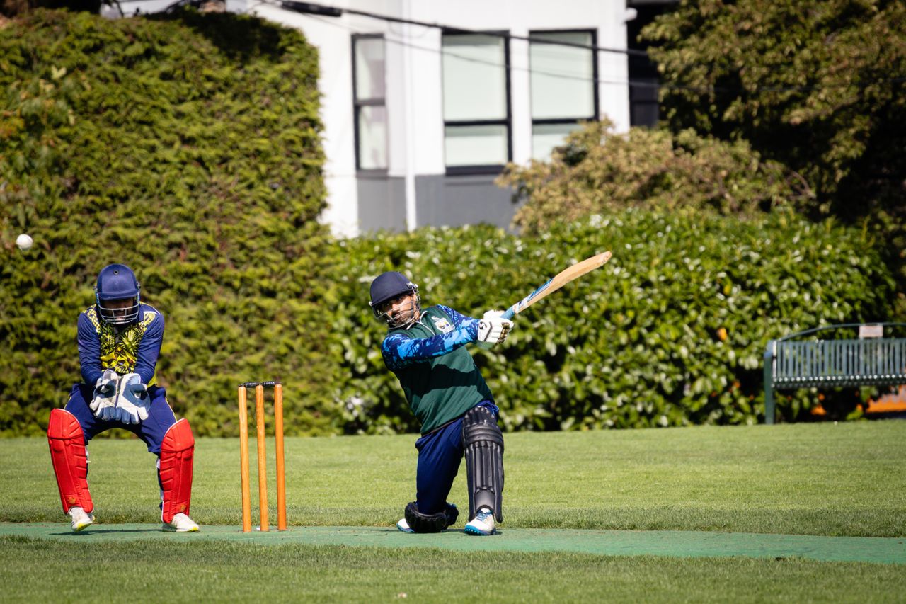 Cricketers in action during a vibrant outdoor cricket match in Victoria, BC.